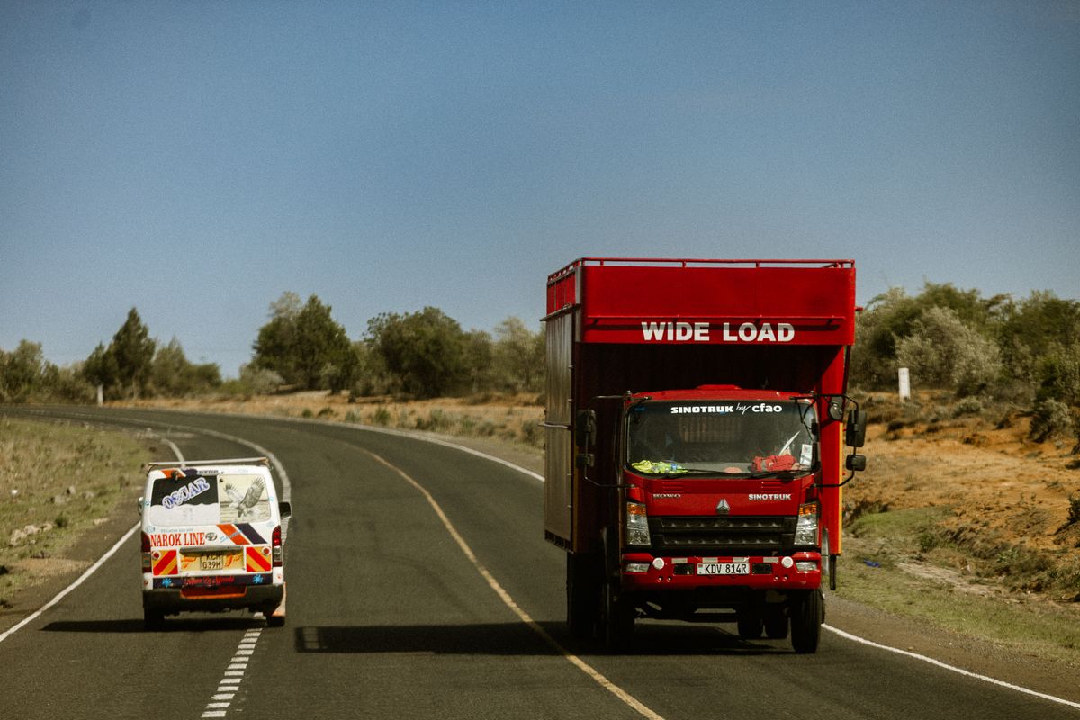 A cargo truck transporting a wide load on a highway in Kenya